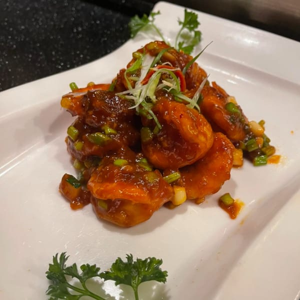 Sweet and sour shrimp with green onions and parsley on a white plate at House of Hunan.