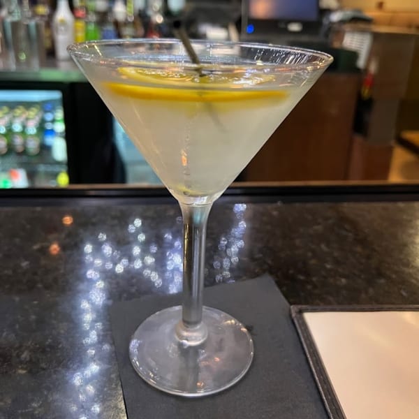 A martini with lemon slices and a straw sits on a dark bar counter at House of Hunan.