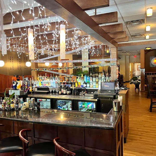 A well-stocked bar at House of Hunan, adorned with festive lights and Halloween decorations.